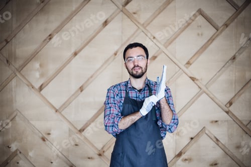 Portrait of a carpenter working in workshop wearing gloves