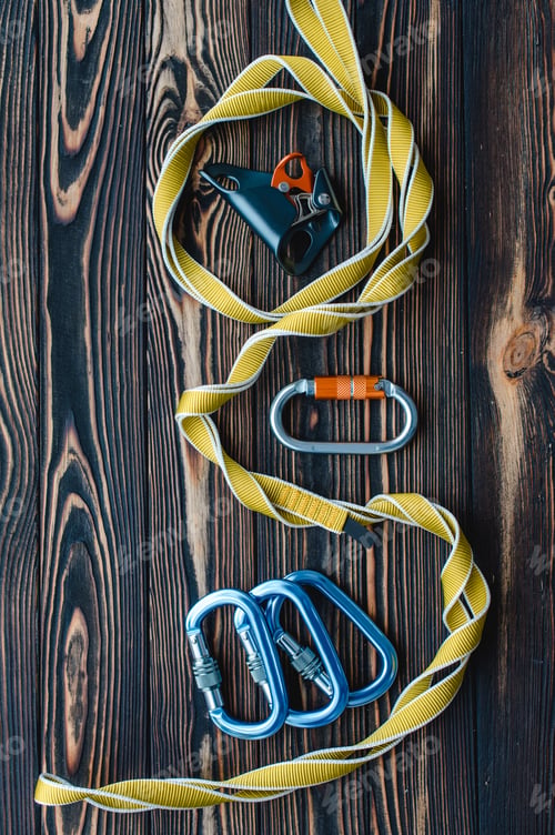 Preview: Isolated photo of climbing equipment. Parts of carabiners lying on the wooden table