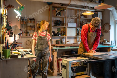 Preview: Carpenter man straightens board corrects defects of wood with hands in wooden workshop with partner.