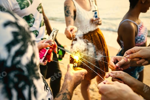 Preview: A diverse group of friends enjoying sparklers at the beach toget
