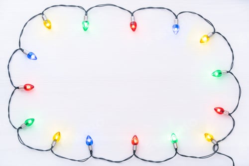 Preview: Multicolored illuminated garland in retro style on a white wooden background with copy space.