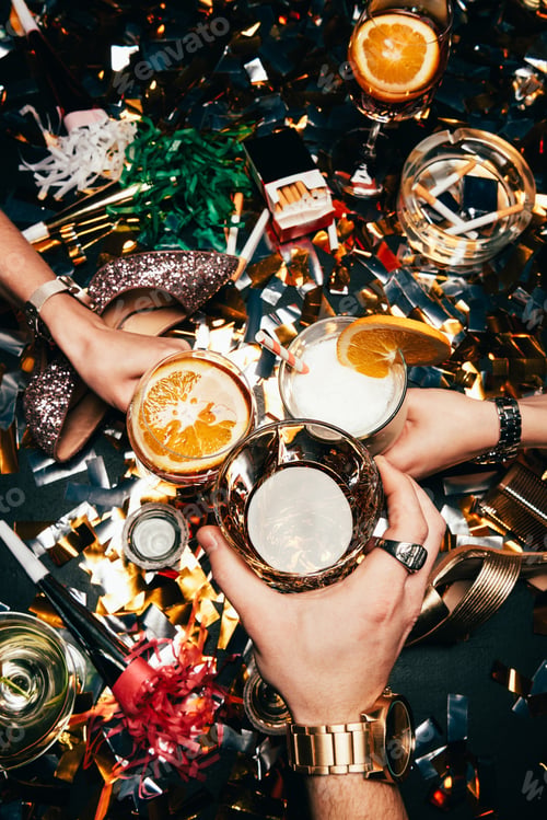 Preview: partial view of friends with luxury watches clinking by glasses with alcohol over table covered by
