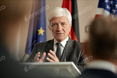Preview: Senior Caucasian Man Speaking at Podium during International Political Event