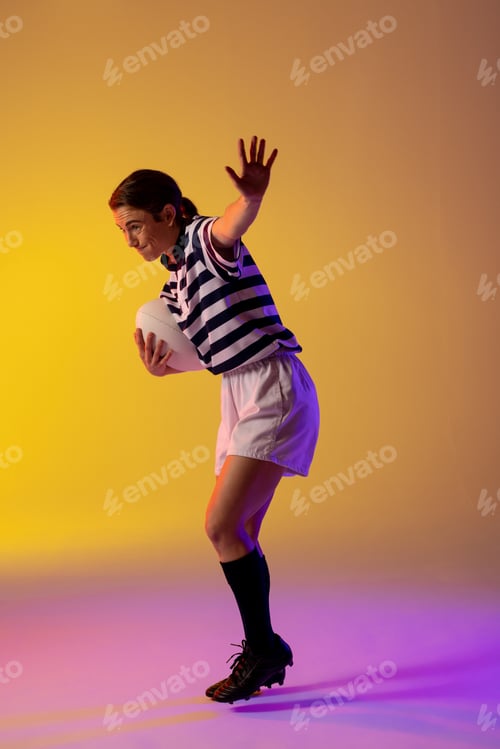 Preview: Caucasian female rugby player with rugby ball over neon pink lighting