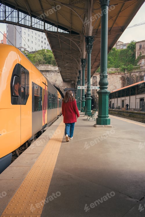 Preview: Woman walking alongside a train at porto railway station during daytime