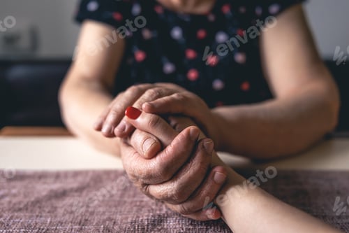 Preview: Old and young man holding hands, close up.