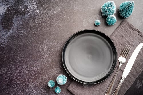 Preview: Christmas table setting with black dishware, silverware and green decorations on dark background