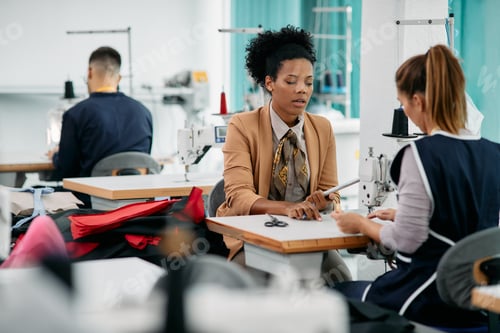 Preview: Black female designer talking to a seamstress at clothing design studio.