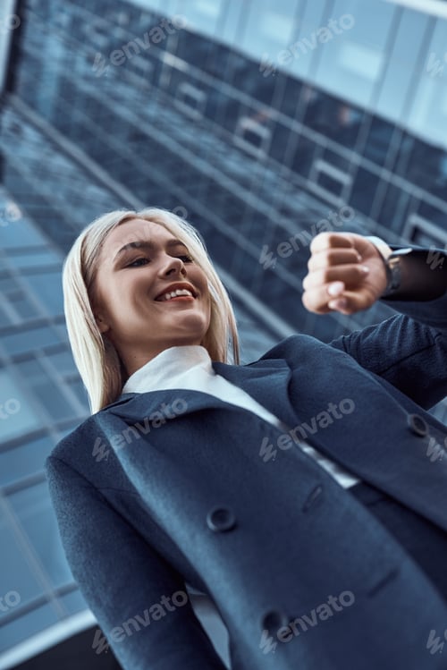 Preview: Woman looking at her wrist watch while going to office checking