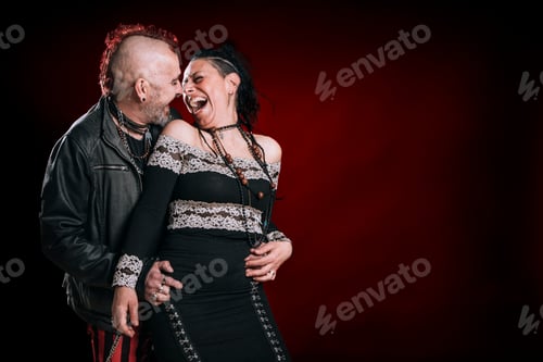 Preview: punk man and woman couple look at each other and laugh excitedly in studio shot