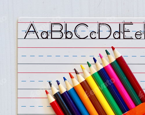 Preview: Overhead view of colored pencils and lined white board with letters used for learning to write