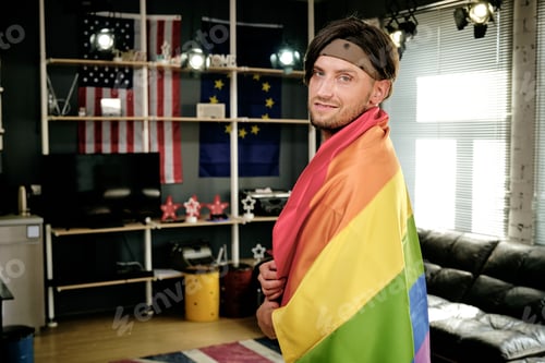 Preview: Young gay man with pride flag standing in front of camera