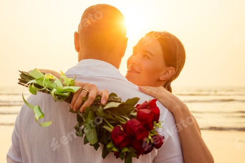 Preview: man giving roses to his surprise and wonder woman on the ocean beach.