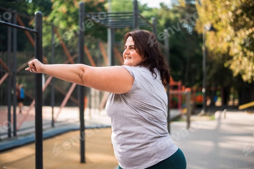 Preview: Woman with overweight doing exercises on a sports field
