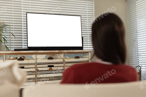 Preview: Rear view of caucasian young woman watching tv while relaxing in living room, copy space