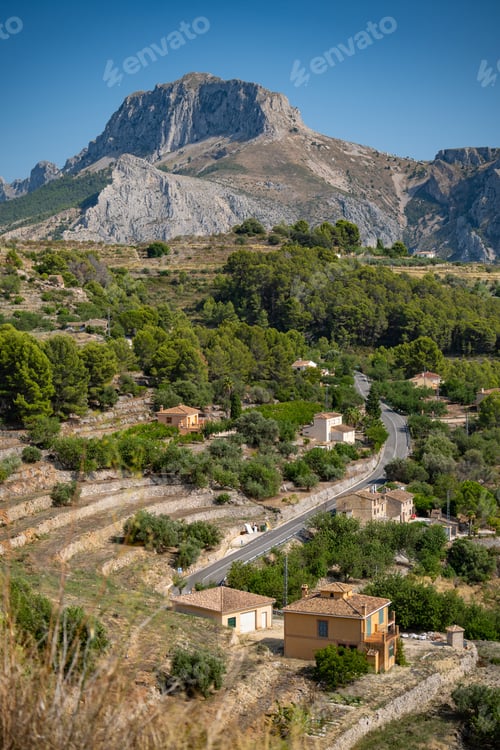 Preview: Serene landscape of mountains and houses along a rural road