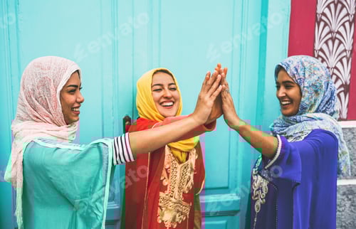 Preview: Happy Arabian women stacking hands together outdoor