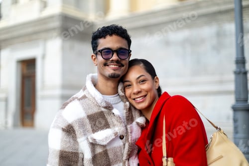 Preview: Happy multi ethnic couple smiling and embracing outdoors in urban setting