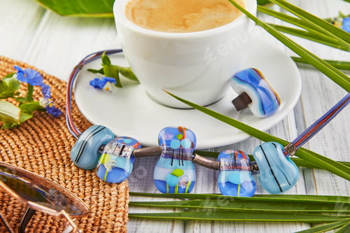 Preview: Summer concept with jewelry. Coffee, palm leaves hat and a ring with a choker on a white wooden