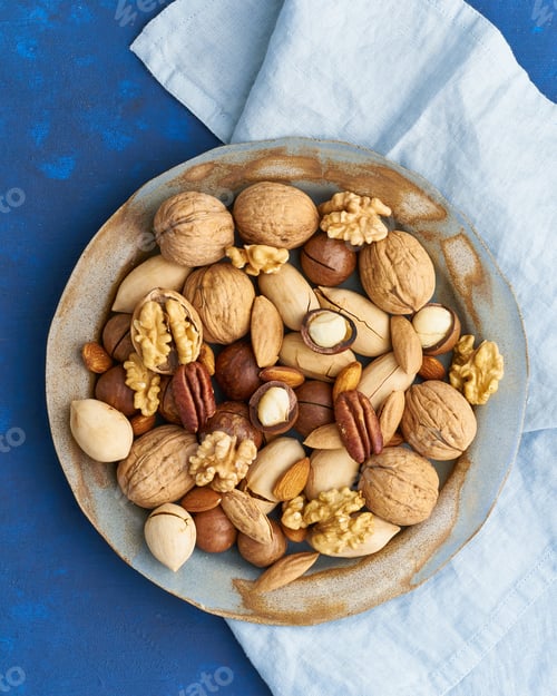 Preview: Classic blue in food. Mix of nuts on plate - walnut, almonds, pecans, macadamia