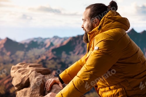 Preview: Young adventure seeker looking out at a scenic mountain range view