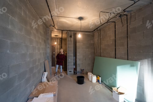 Preview: Woman in Jacket Inspecting Unfinished Gray Interior