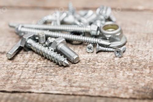 Preview: Collection of assorted metal fasteners on a wooden surface in a workshop setting