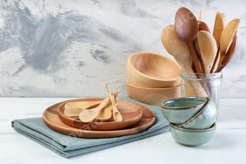 Preview: Different dishware and utensils on white marble table against textured wall