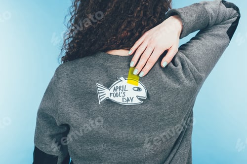 Preview: back view of woman with hand drawn fish on back, april fools day concept