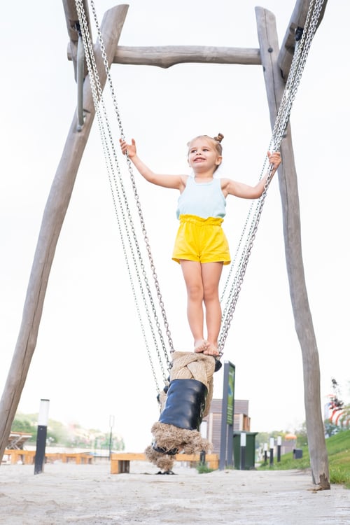 Preview: cute little child girl in colorful clothes playing on kids playground in summer day