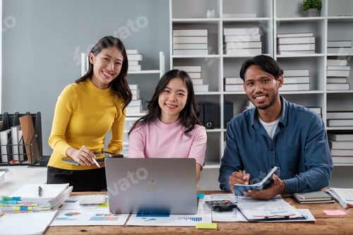 Preview: Group of young Asian business people brainstorming, looking at laptop computer.