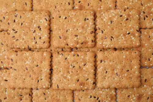 Preview: Cereal crackers with flax and sesame seeds as background, top view