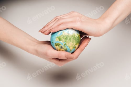 Preview: partial view of woman holding earth model on white background, global warming concept
