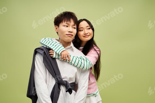 Preview: Couple sharing a loving moment in stylish outfits against a vibrant green backdrop