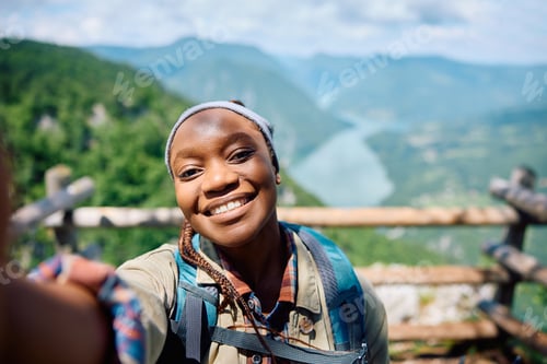 Preview: Happy black woman taking selfie while hiking in the mountains.