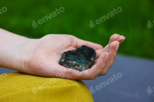 Preview: Woman meditating with crystal to heal or restore her aura outdoors, closeup