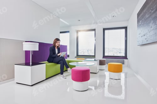 Preview: Young businesswoman using tablet in office lounge