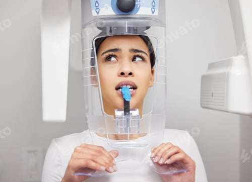 Preview: Shot of a young woman looking anxious while using an x ray machine at a dentists office