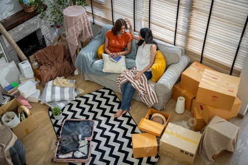 Preview: Two women are sitting on a couch, one reading a book