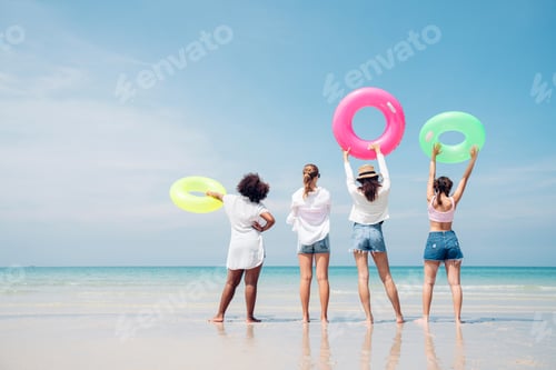 Preview: Group of teenage with floaty on the beach having fun.