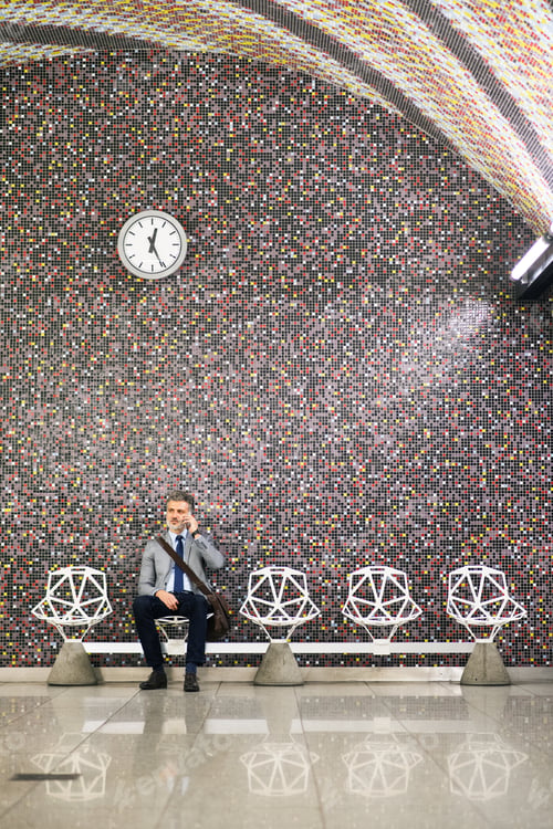 Preview: Mature businessman with smartphone in a metro station.
