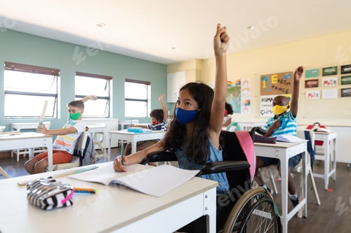 Preview: Disable girl wearing face mask raising her hand while sitting on wheelchair in class