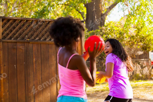 Preview: Girl chasing friend with water balloon in garden