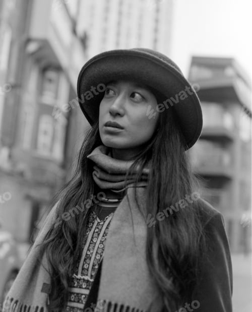 Preview: Young woman wearing hat and scarf looking up in black and white analog photo