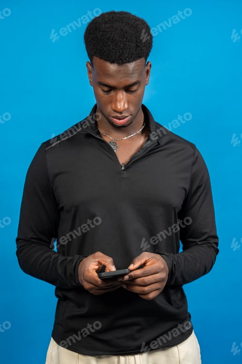 Preview: Young man using mobile phone on blue background