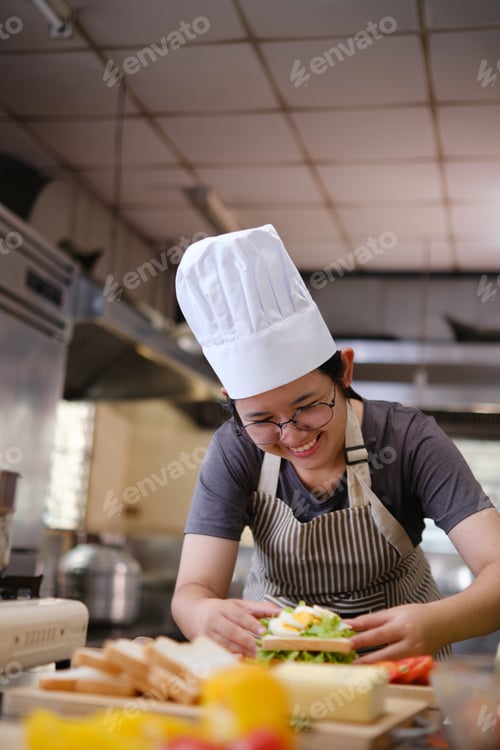 Preview: Focused chef carefully a gourmet sandwich in a professional kitchen with fresh ingredients in view