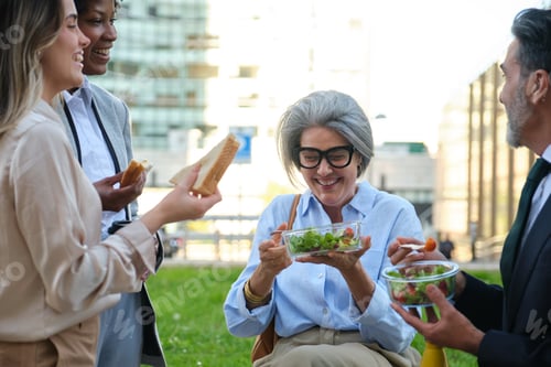 Preview: Business people eating healthy food outdoors during lunch break