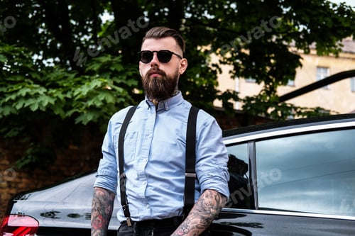Preview: Attractive bearded man is leaning on his car.