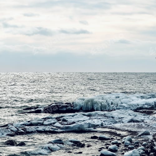 Preview: Shimmering water with icy snow covered rocks, peaceful winter landscape