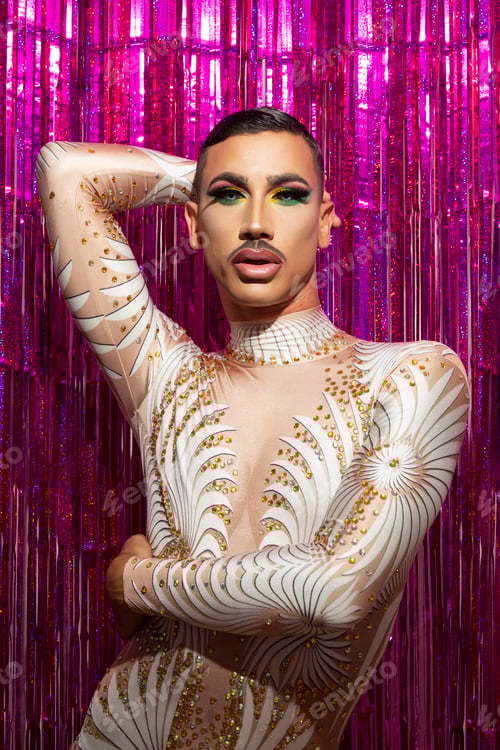 Preview: young drag queen with short hair and mustache posing with fuchsia color background